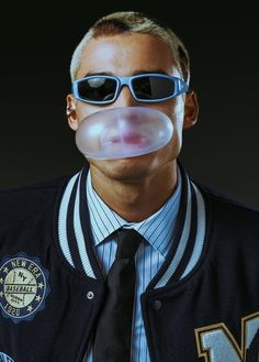 a man wearing sunglasses and a tie with bubble attached to his mouth is making a funny face