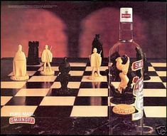 a chess board with figures on it and an empty bottle in the foreground,