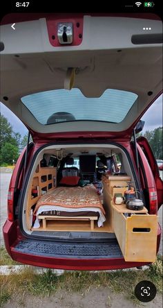 the back end of a red car with an open trunk filled with furniture and items