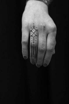 a black and white photo of a person's hand with a tattoo on it