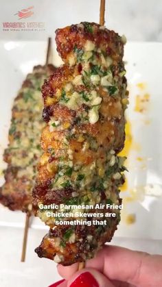 someone is holding up a piece of food on a skewer with the caption, garlic parmesan air fried chicken and something that's something that