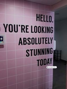 there is a pink tiled wall with black words on it that says, hello you're looking absolutely stunning