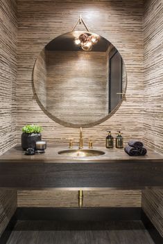 a bathroom with a round mirror above the sink and wooden flooring on the walls