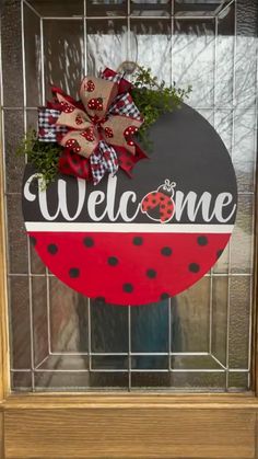 a welcome sign with a ladybug and bow on it in front of a window
