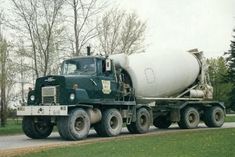 a green and white cement truck driving down the road