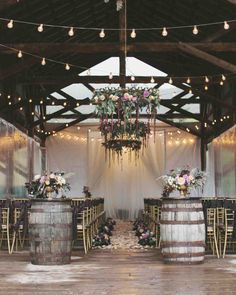 the inside of a barn with wooden barrels and flowers