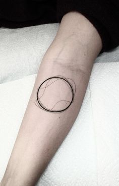 a black and white photo of a person's arm with a circle tattoo on it
