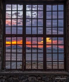 an open window looking out onto the ocean at sunset or sunrise with mountains in the distance