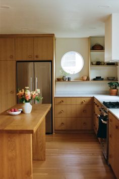 a kitchen with wooden cabinets and an island in front of the stove top is filled with flowers