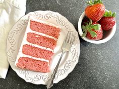 a piece of red velvet cake on a plate with strawberries and fork next to it