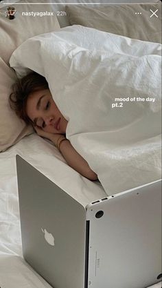 a woman laying in bed with an apple laptop on her side, under the covers