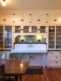 a kitchen with white cabinets and black counter tops is lit by lights from above the sink