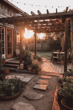the sun is setting on an outdoor patio with potted plants and lights strung over it