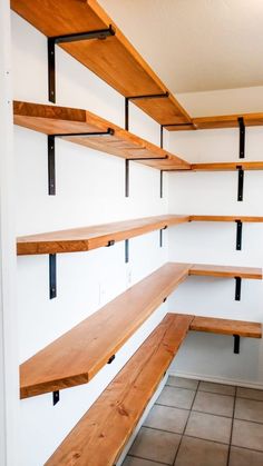 empty wooden shelves in the corner of a room with tile flooring and white walls
