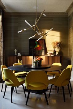 a modern dining room with yellow chairs and a black table in front of a large window