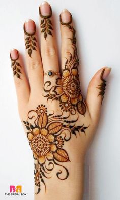 a woman's hand with henna tattoos and flowers on the palm, which is decorated