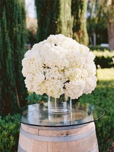 a vase filled with white flowers sitting on top of a barrel