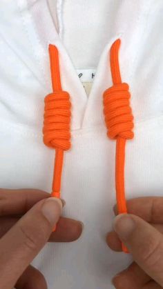 two hands holding an orange rope attached to a white shirt