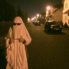 a person in a nun costume is walking down the street at night with a cell phone