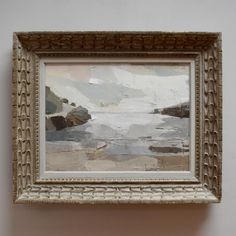 a painting hanging on the wall above a white framed art piece with an ocean scene