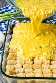 a casserole dish with tater tots and cheese being poured into it