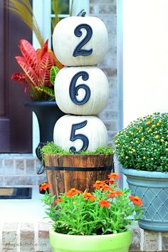 three pumpkins stacked on top of each other in front of a house with flowers