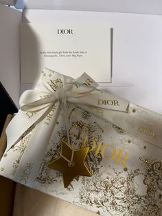 an open dior gift box with a white ribbon and gold foil on the front