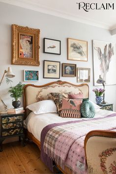 a bed sitting in a bedroom next to pictures and paintings on the wall above it