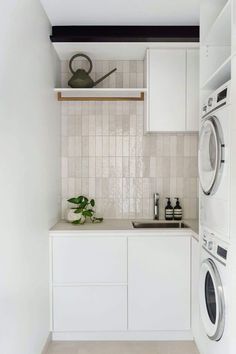 a washer and dryer in a small room with white cabinets on the wall