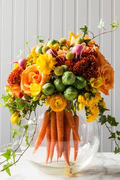 a vase filled with flowers and carrots on top of a table