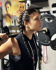 a woman holding a barbell in her hand and looking at the wall behind her