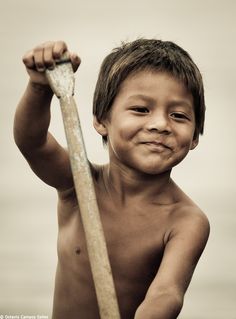 a young boy holding a baseball bat in his right hand and smiling at the camera