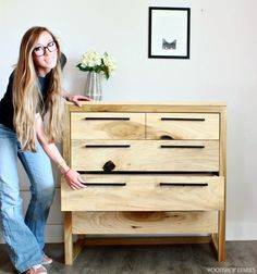 a woman standing next to a wooden dresser with drawers on each side and one drawer open