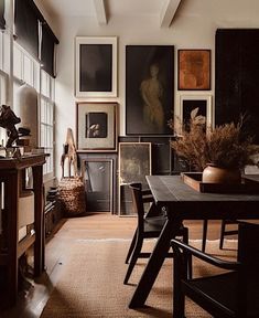 a room filled with lots of framed pictures and art on the wall next to a wooden table