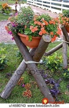 two potted plants sitting on top of wooden poles in the grass with flowers growing out of them