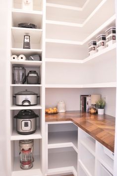 an organized pantry with white shelves and wooden counter tops