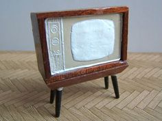 an old fashioned tv sitting on top of a wooden table next to a small black and white object