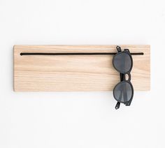 a pair of sunglasses hanging on a wooden board with eyeglasses attached to it