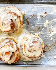 four cinnamon rolls sitting on top of a baking pan