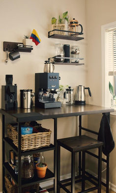 a coffee bar with two stools next to it and shelves on the wall above