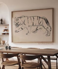 a dining room table and chairs in front of a framed tiger print on the wall