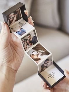 a woman holding an open box with photos inside it and the lid opened to show pictures