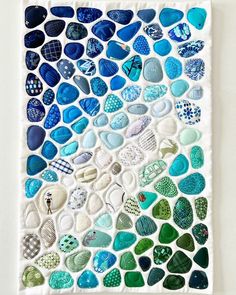 a piece of art made out of blue and green pebbles on a white background with text overlay that says how to make sea glass mosaics