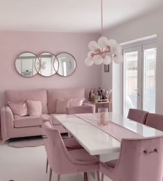 a living room filled with pink furniture and mirrors on the wall above a white table