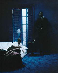 a man standing next to a bed in a dark room