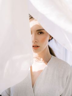 a woman standing under a white sheet looking at the camera