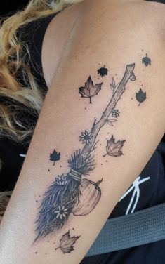 a woman's arm with an arrow and leaves tattoo on the back of her shoulder