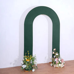 two vases filled with flowers sitting on top of a wooden floor next to a green arch