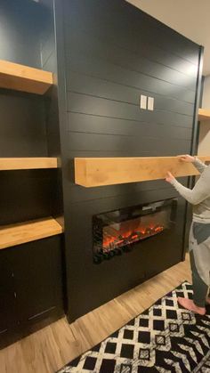 a person standing in front of a fireplace with shelves on each side and a fire place at the top