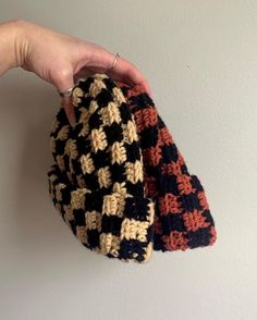 a hand is holding two crocheted hats